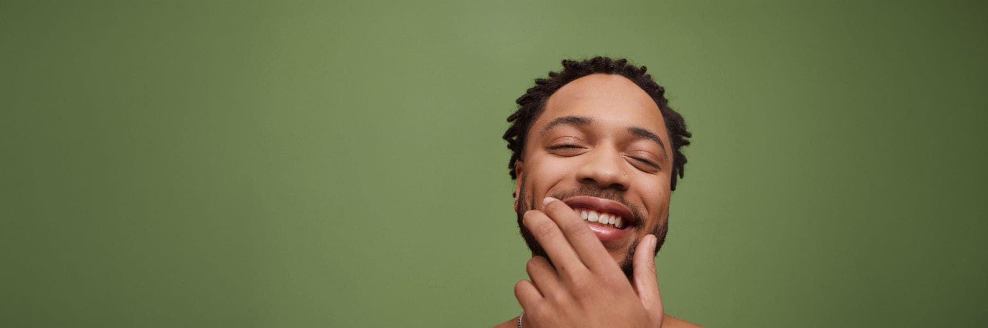A relaxed, smiling man against a green backdrop
