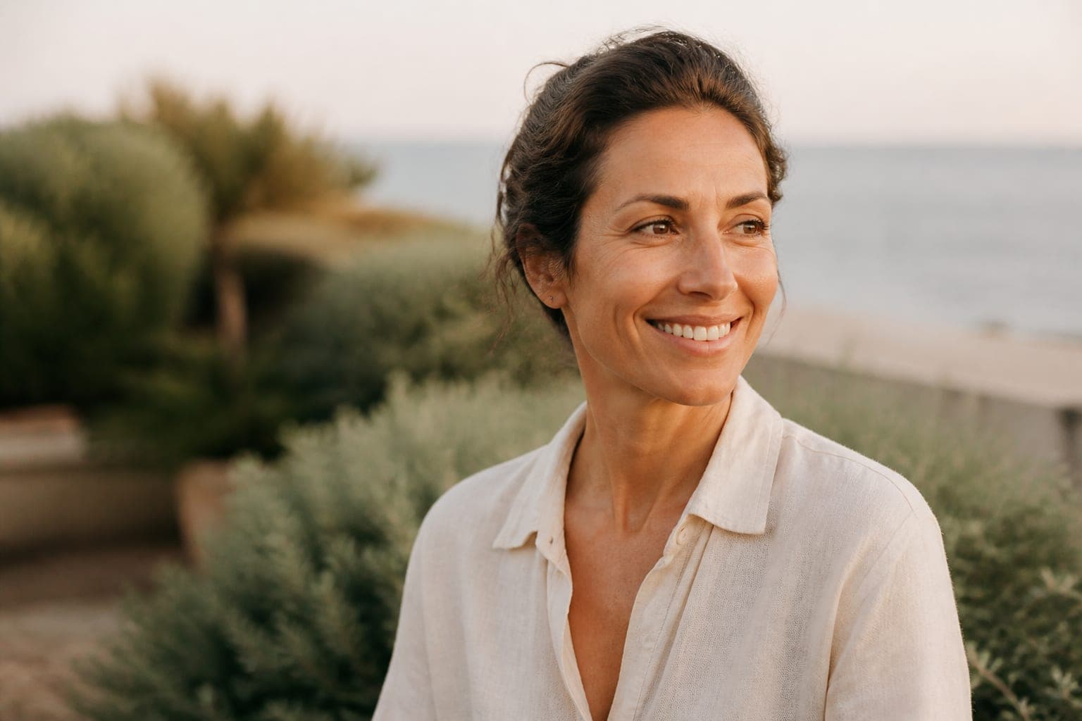 A woman smiling outdoors in warm evening light